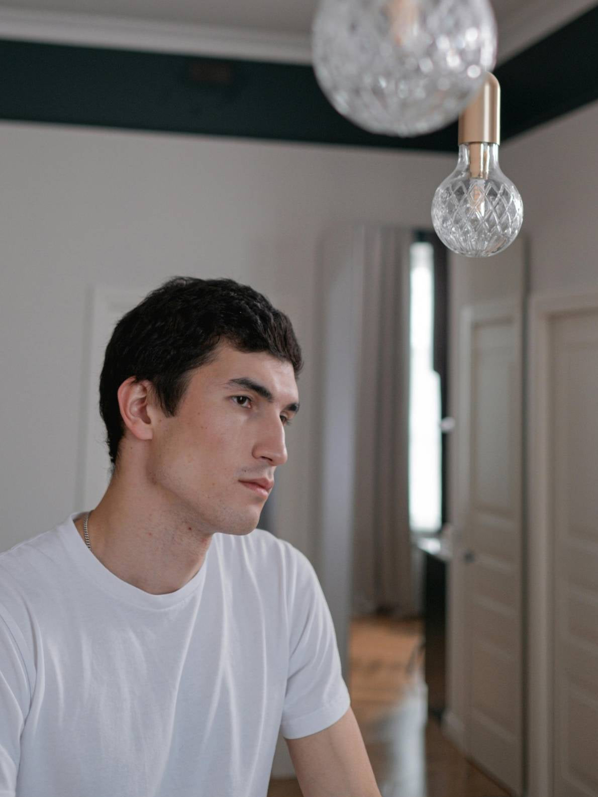 Junger Mann mit einem leichten weißen Baumwollshirt gekleidet in einer stylischen Wohnung