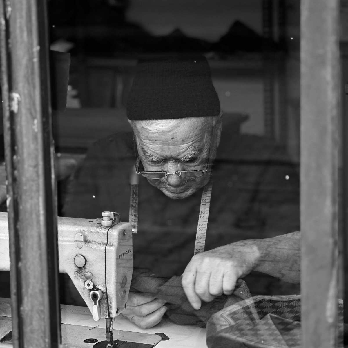 Schneider bei der Arbeit an einer Nähmaschine, Symbol für traditionelles Handwerk und hochwertige Textilherstellung