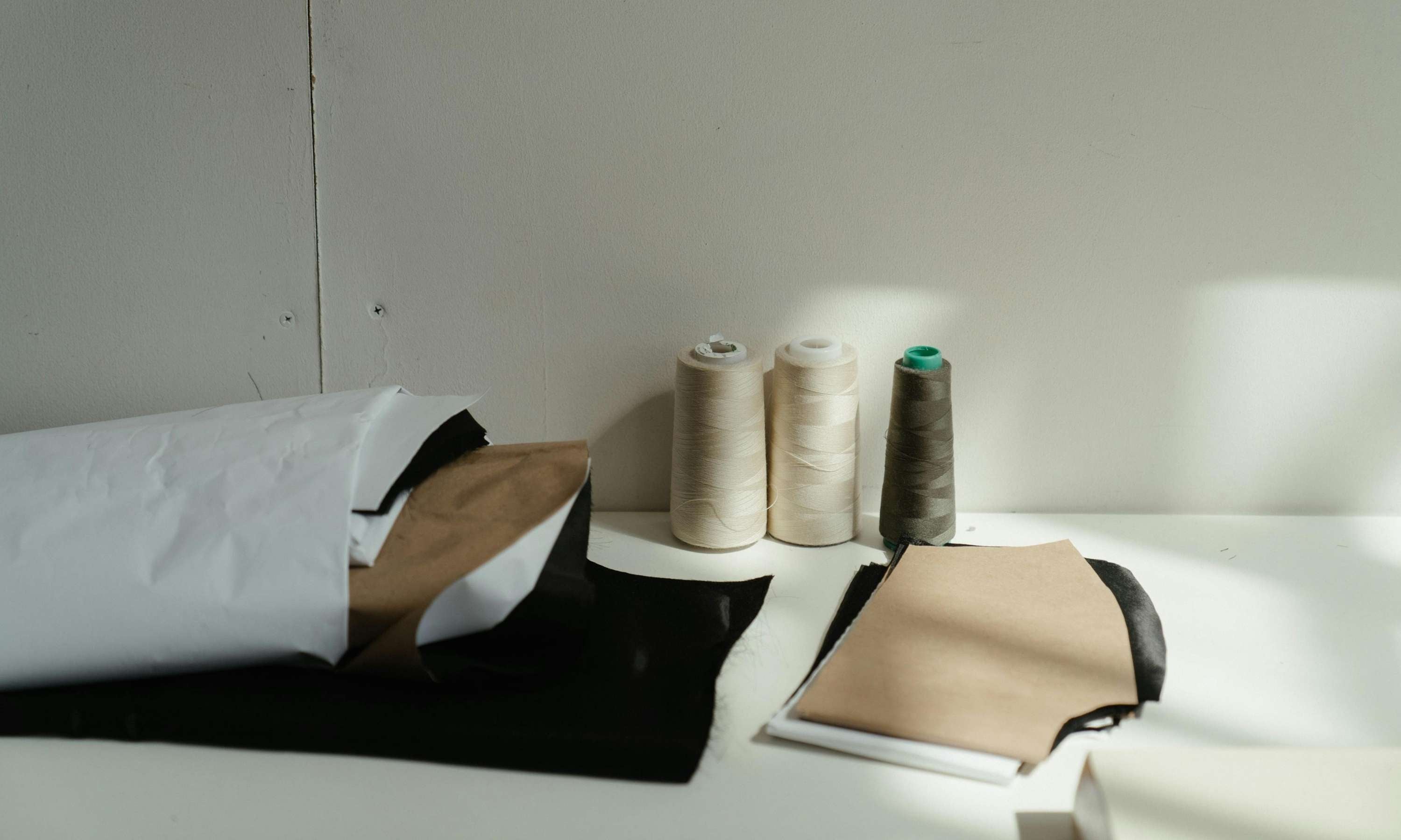 Stoffe und Schnittmuster in natürlichen Farben auf einem weißen Tisch vor einer weißen Wand